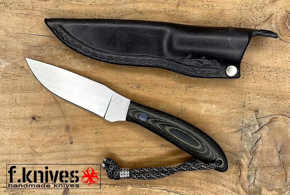Ein feststehendes Messer von f.knives neben seiner schwarzen Lederscheide auf einem Holzbrett